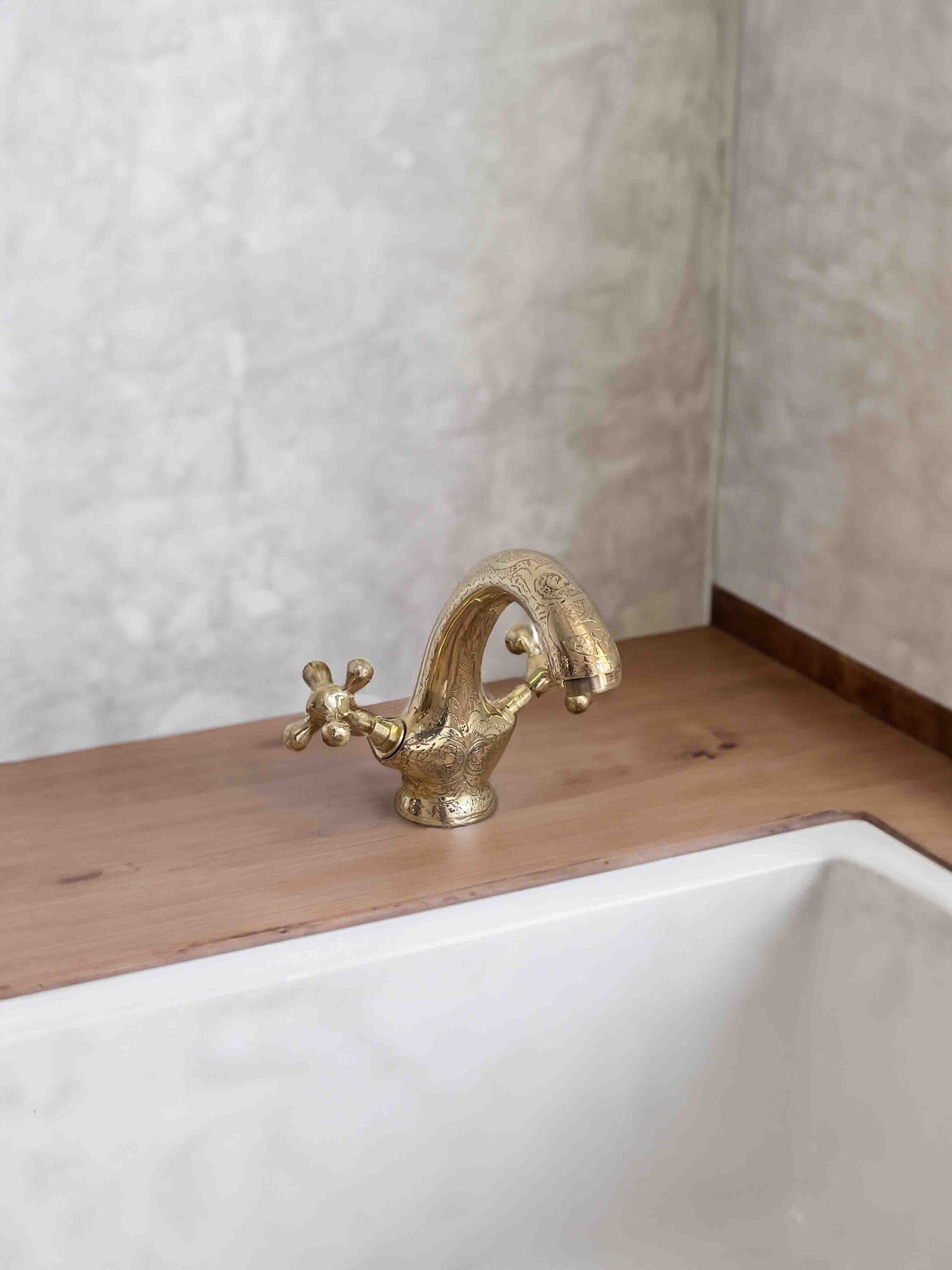 a gold faucet sitting on top of a wooden counter