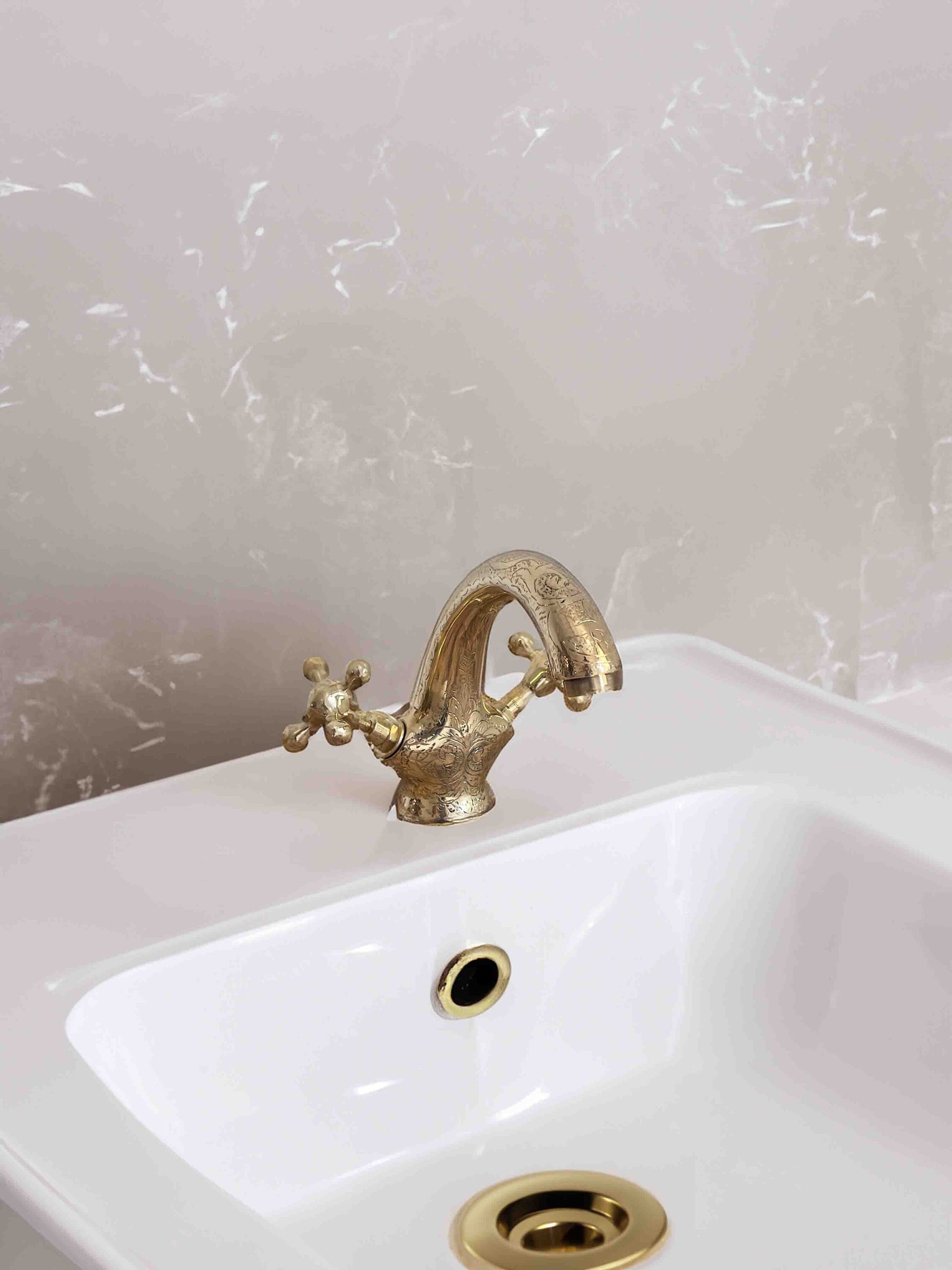 a white sink with a gold faucet in a bathroom