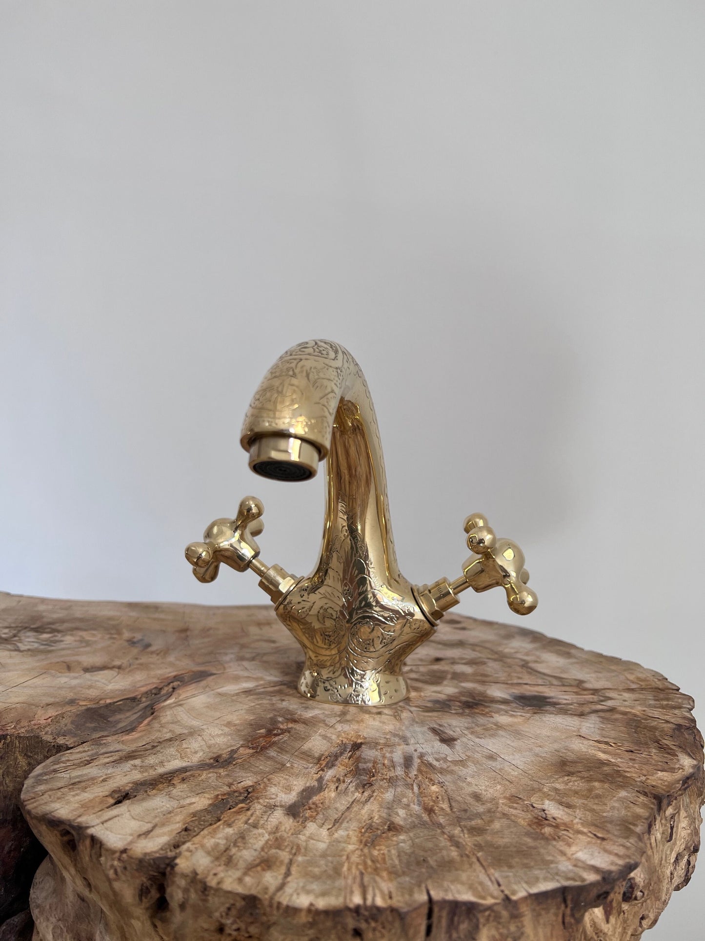 a brass faucet on a tree stump