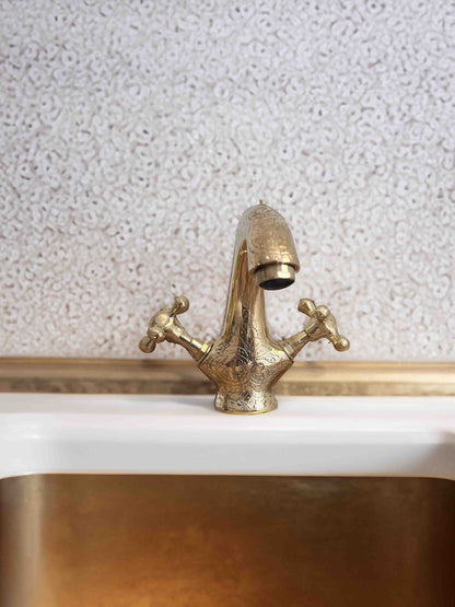 a golden faucet sitting on top of a white sink