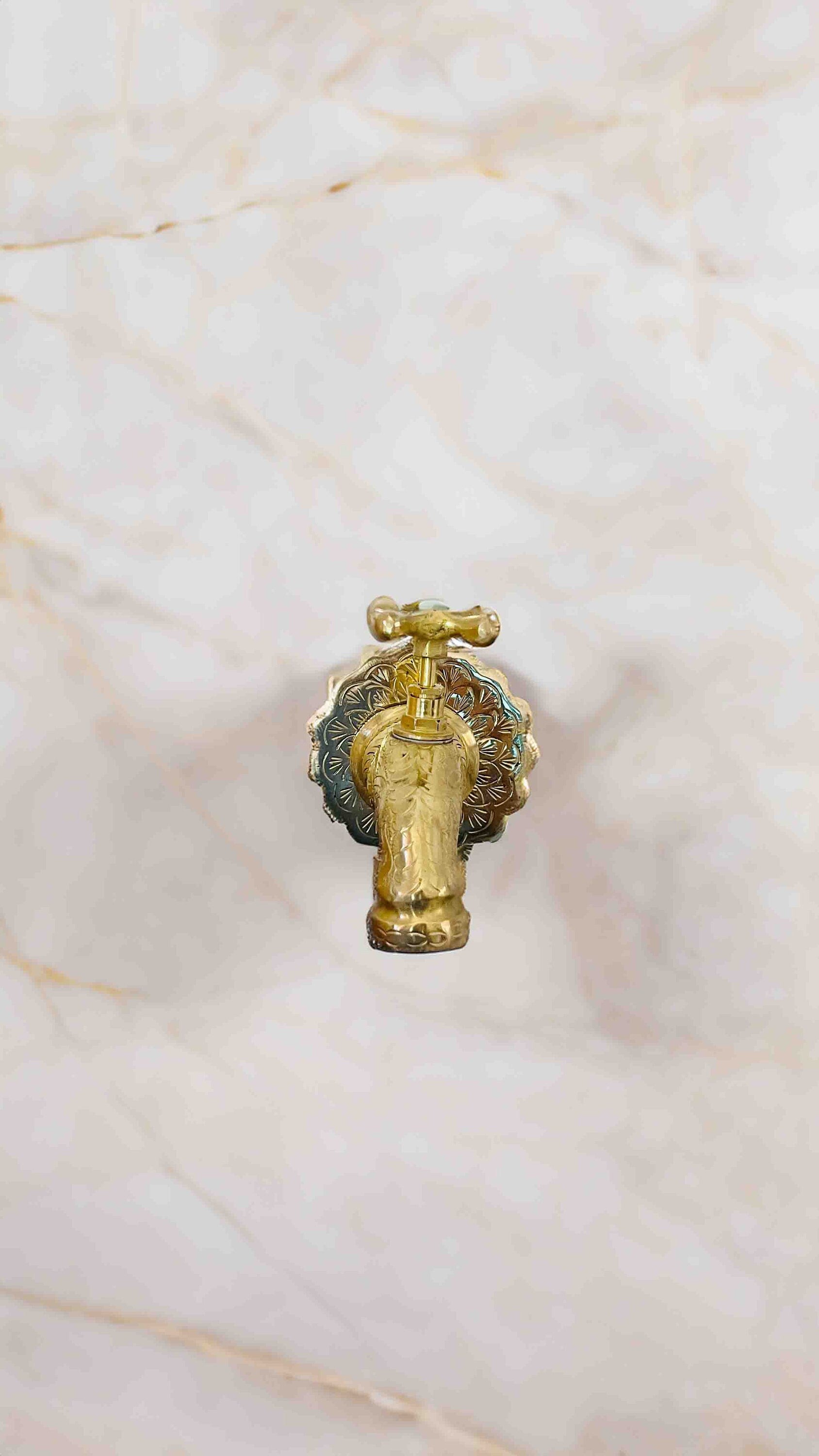 a golden faucet on a marble wall