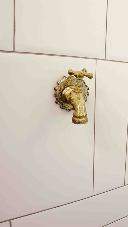 a brass faucet on a white kitchen wall