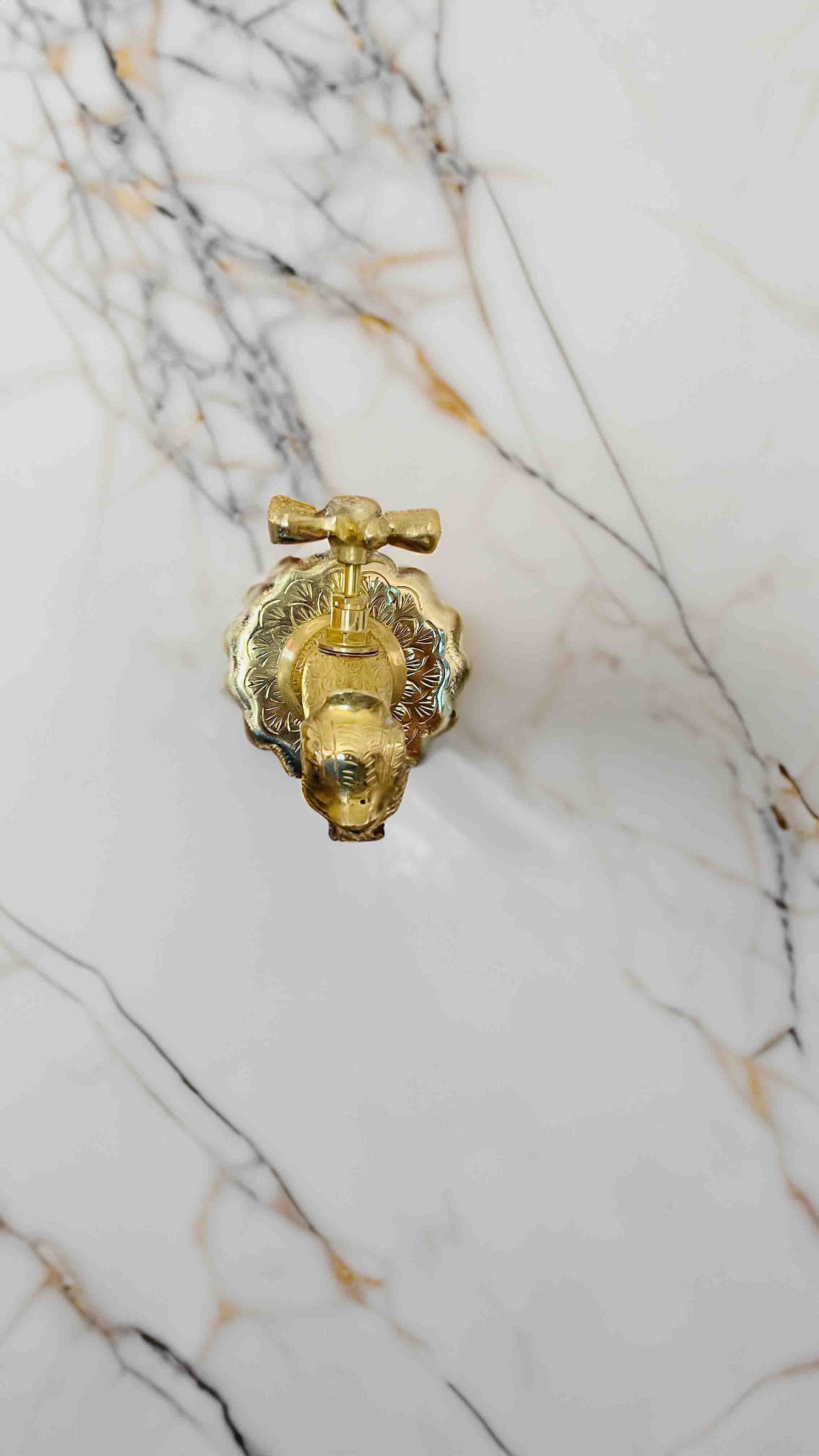 a golden faucet on a marble wall