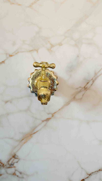 a golden faucet on a white marble wall