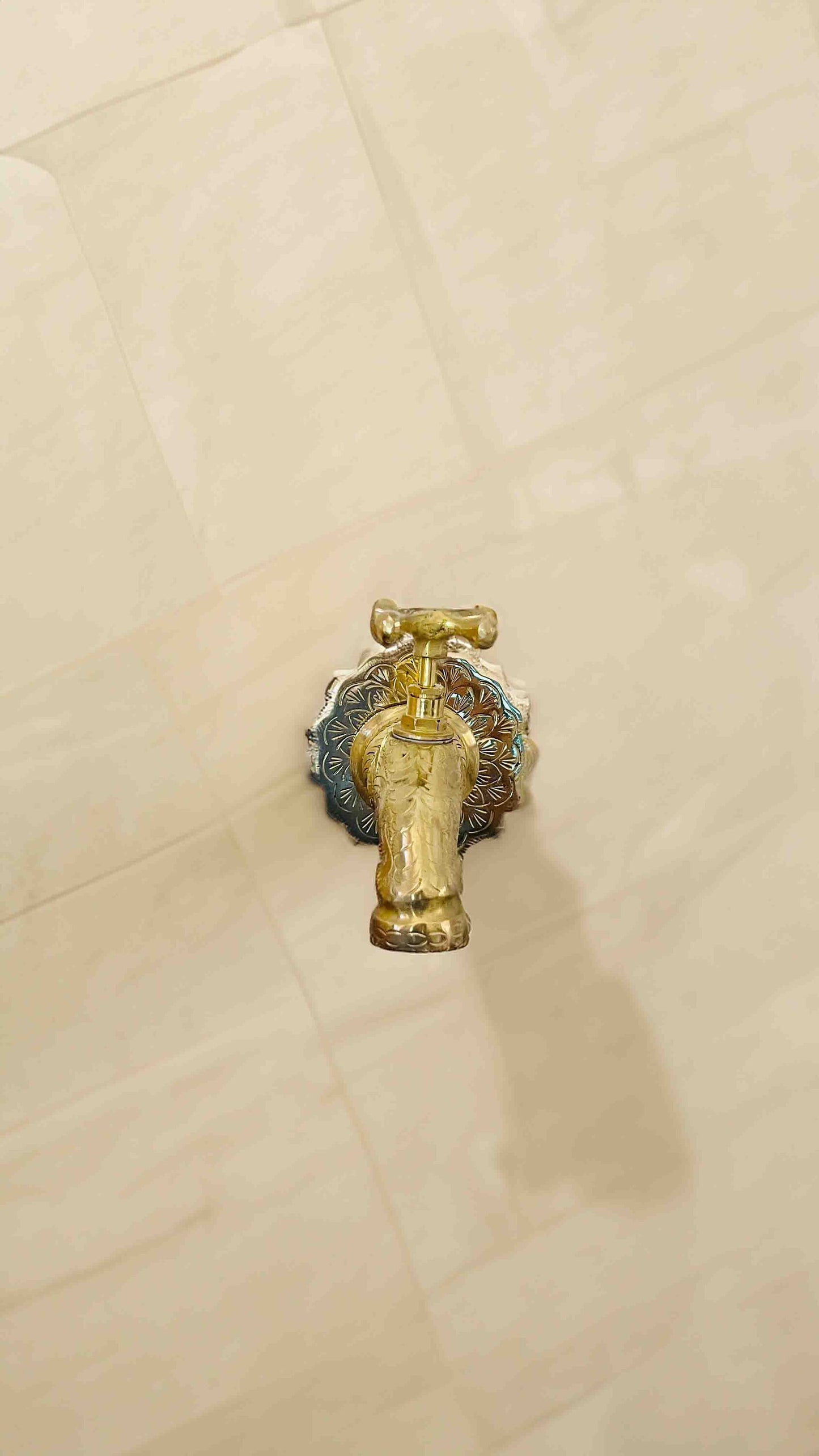 a golden faucet on a white tiled floor