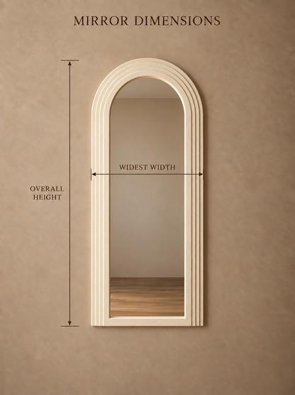 An arched cream-colored wall mirror with a fluted frame, shown on a textured beige wall with dimension lines and text indicating overall height, widest width, and mirror dimensions.