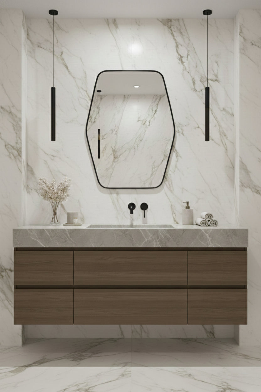 Hexagonal brass mirror over floating wood vanity in marble bathroom.