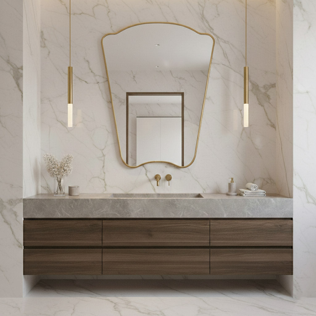 Asymmetrical Italian brass mirror on marble wall above modern wood vanity