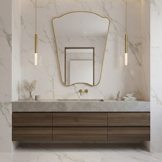 Asymmetrical Italian brass mirror on marble wall above modern wood vanity