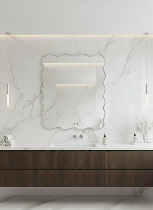 Scalloped silver brass mirror over modern marble bathroom vanity.