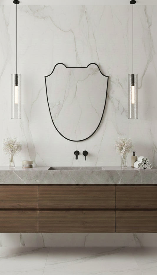 Black brass Italian shield mirror above a marble bathroom vanity
