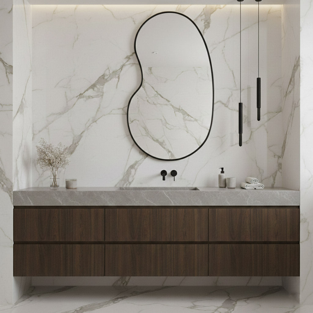 Black kidney mirror in marble bathroom setting.