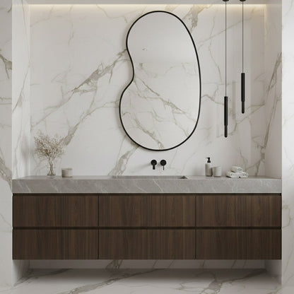 Black kidney mirror in marble bathroom setting.