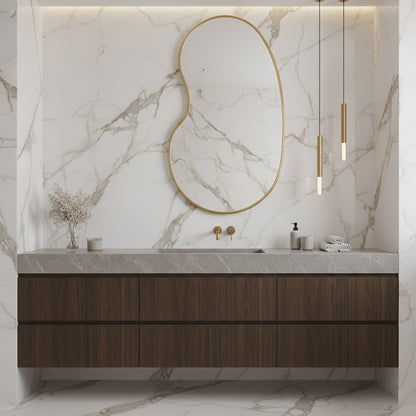 Brass kidney mirror over marble bathroom vanity.