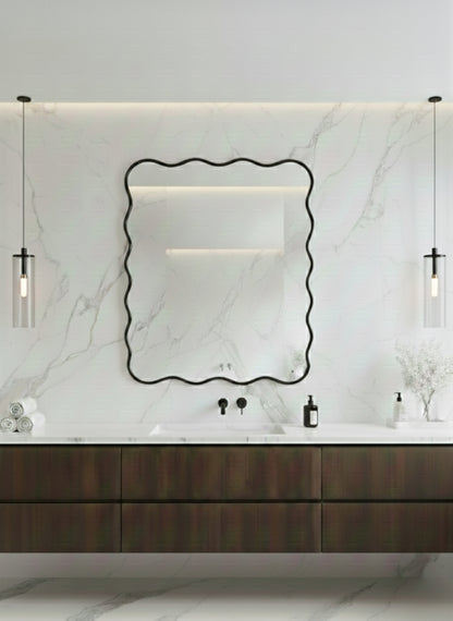 Wavy black brass mirror above modern marble bathroom vanity.