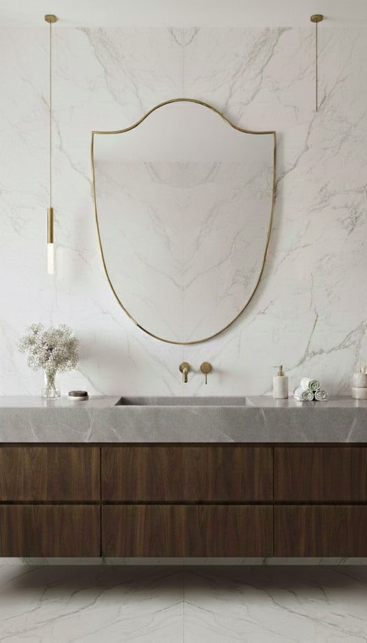 Italian brass shield mirror above marble bathroom vanity