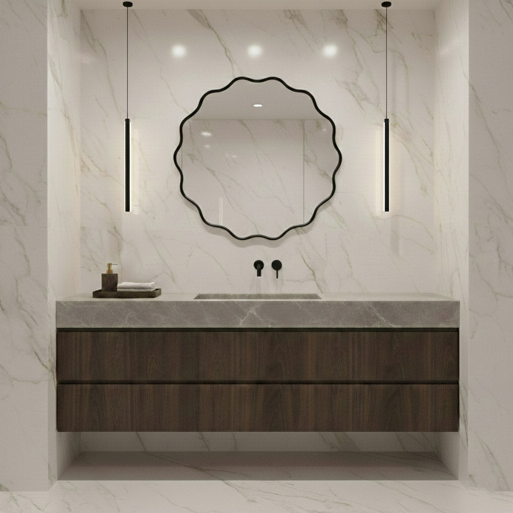 Round wavy black mirror above dark wood vanity in marble bathroom.