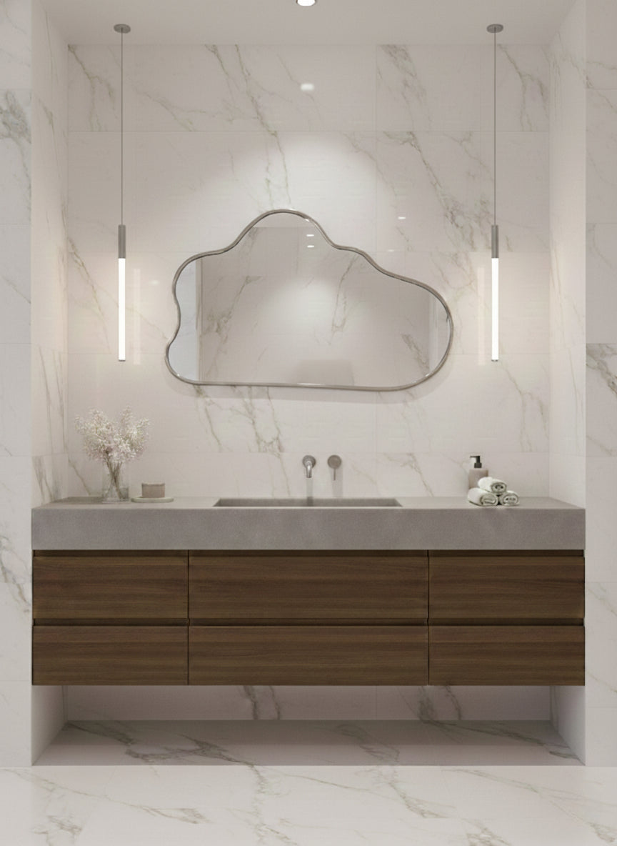 Silver brass cloud mirror above wood floating vanity in marble bathroom.
