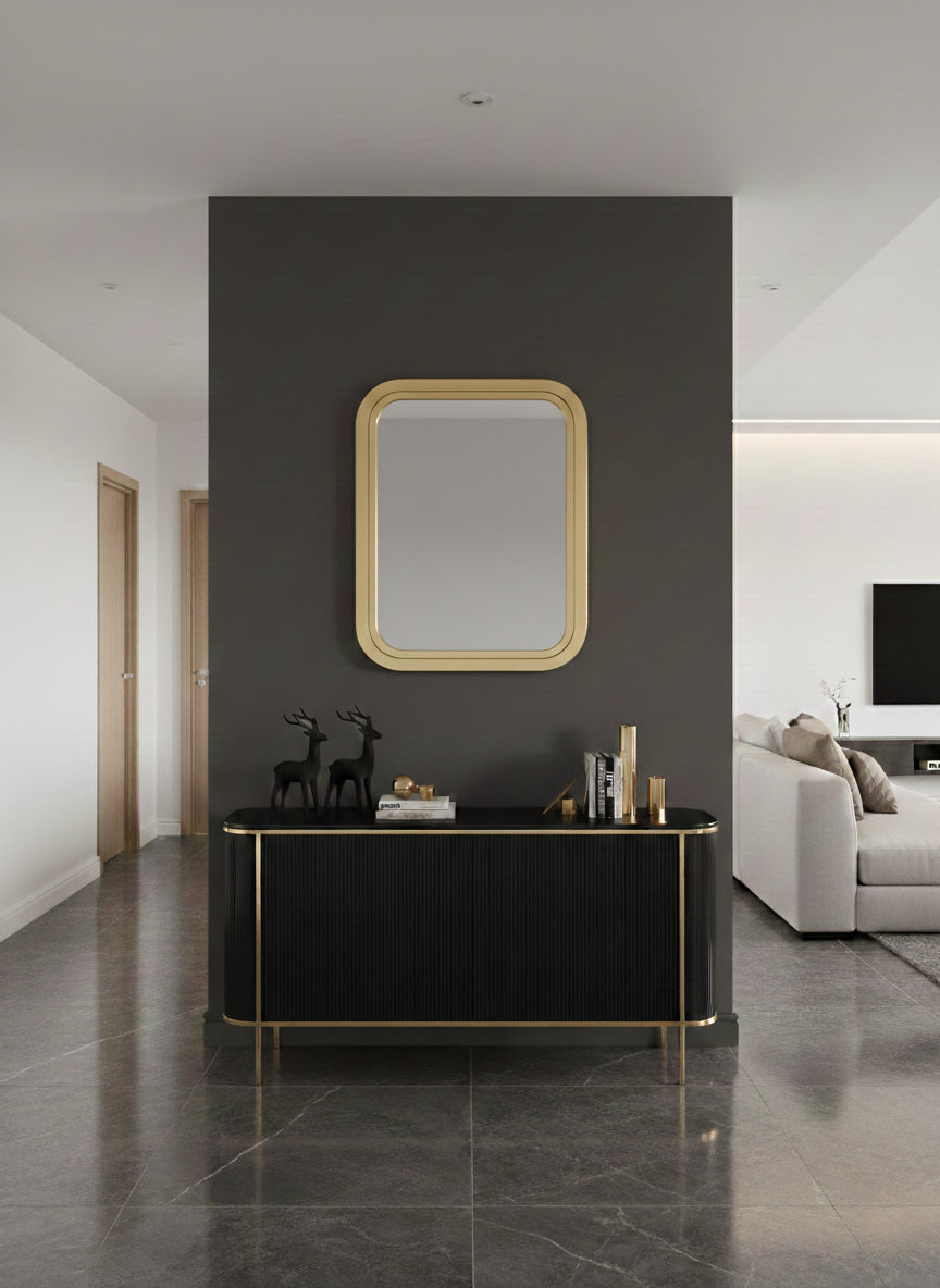 Rectangular brass mirror styled above a black console in a modern living space
