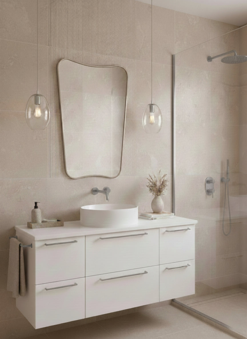 Silver asymmetrical mirror above white floating vanity.