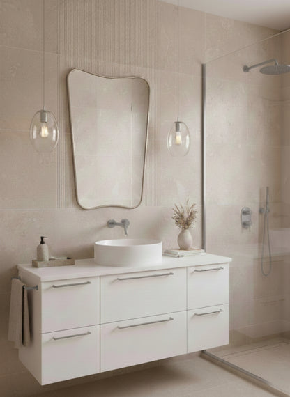 Silver asymmetrical mirror above white floating vanity.