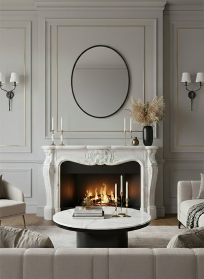 Living room with a fireplace, round mirror, and decorative items.