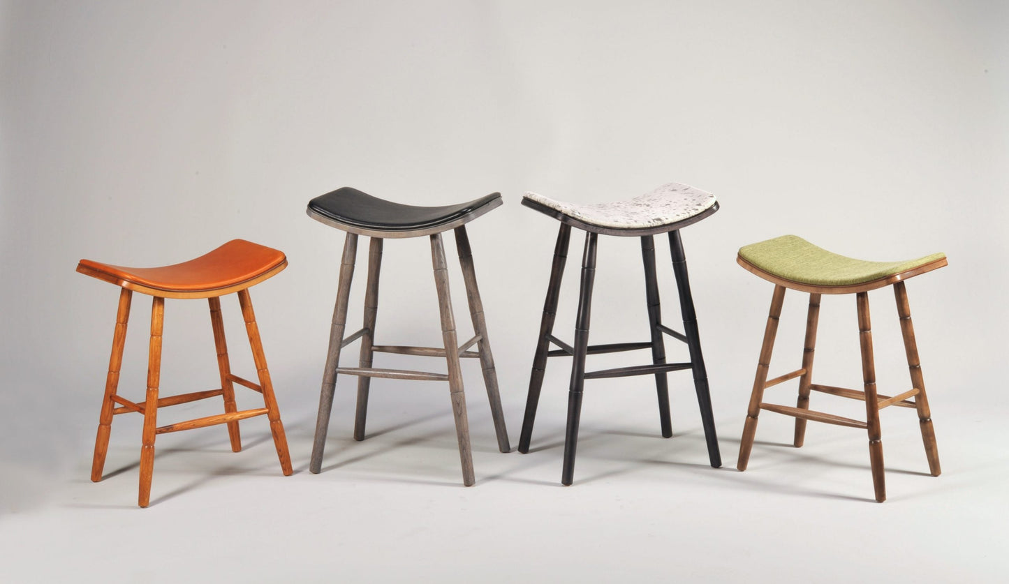 Four stools with different colored seats on a gray background