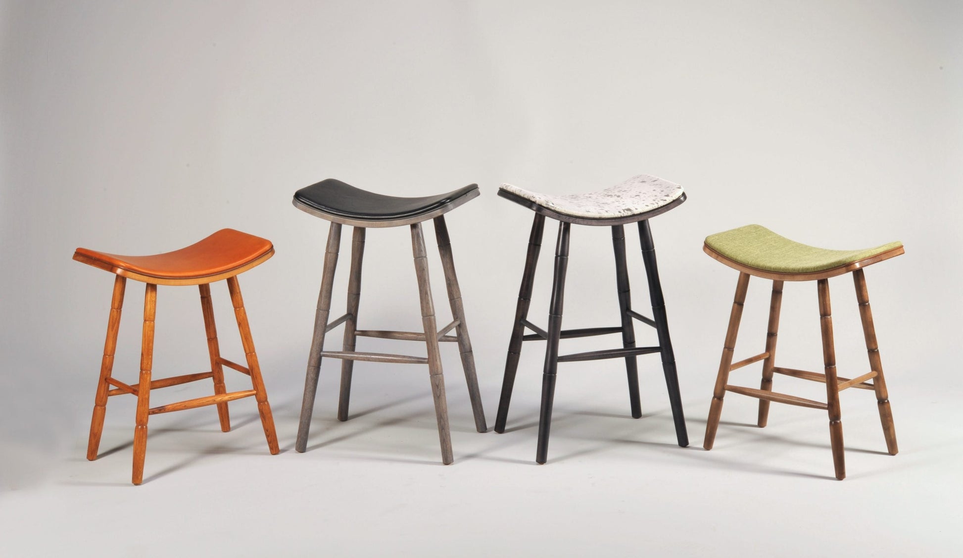 Four stools with different colored seats on a gray background