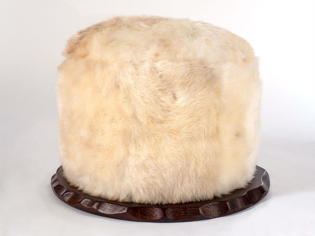 White fur hat on a wooden stand against a white background