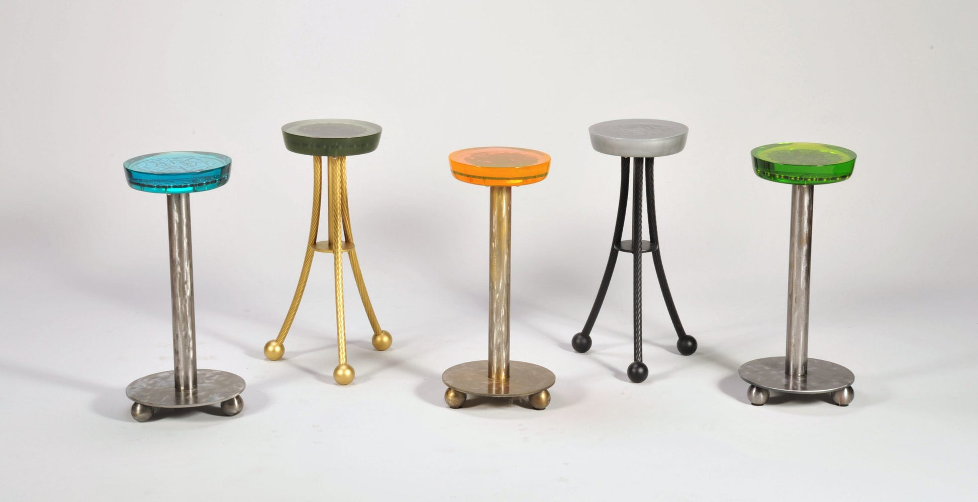 Five colorful stools with different designs on a white background