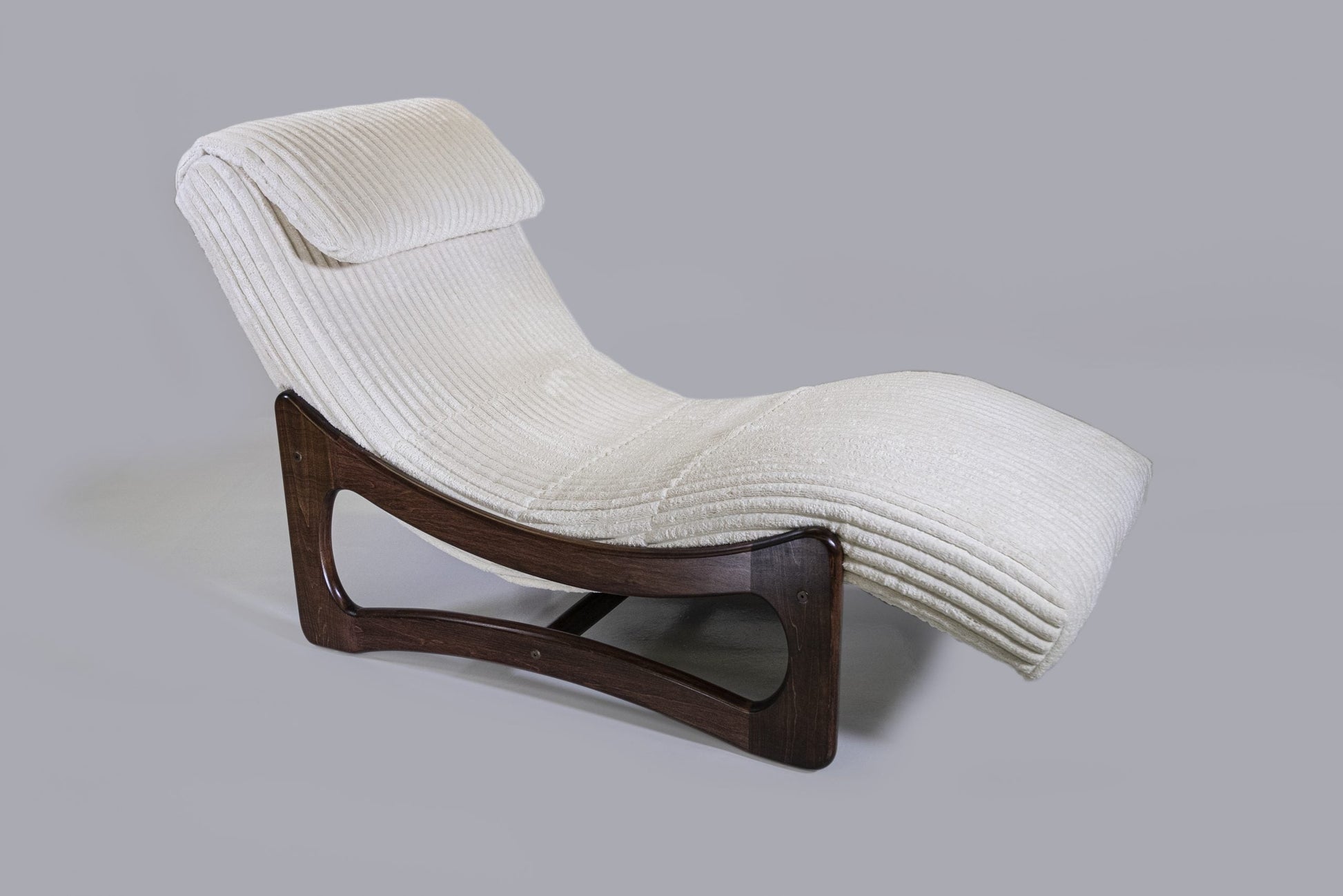 Modern lounge chair with ribbed white backrest and wooden base on a gray background