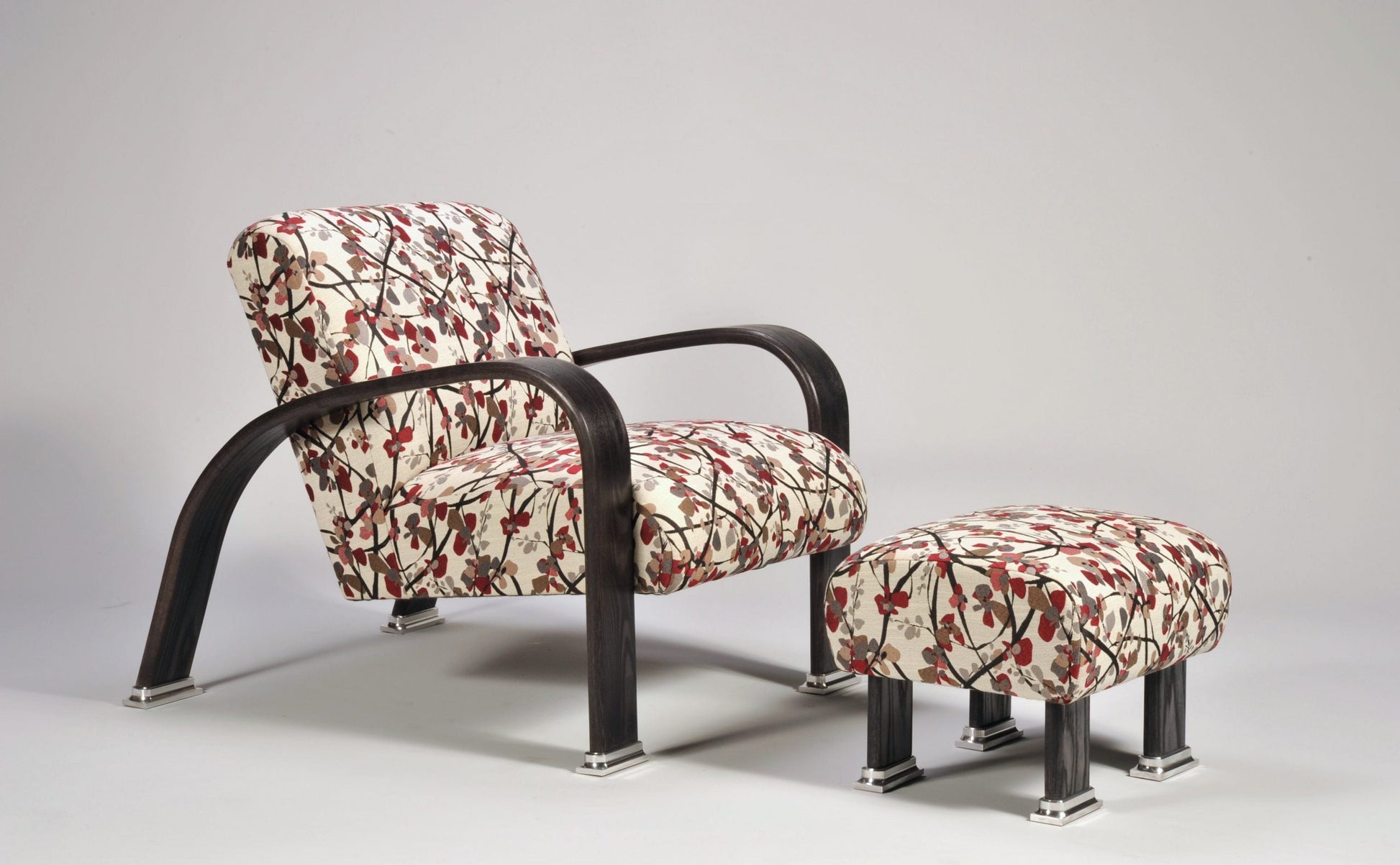 Floral-patterned armchair and ottoman with black metal frames on a gray background