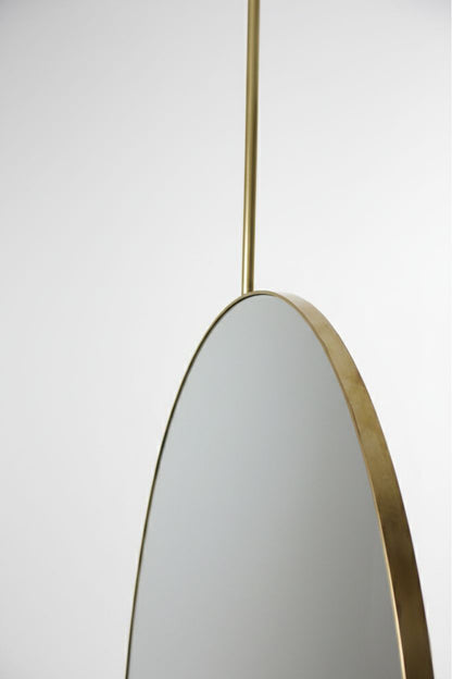 Close-up of oval brass mirror frame and ceiling rod