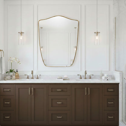 Shield wall mirror with brass frame above double bathroom vanity