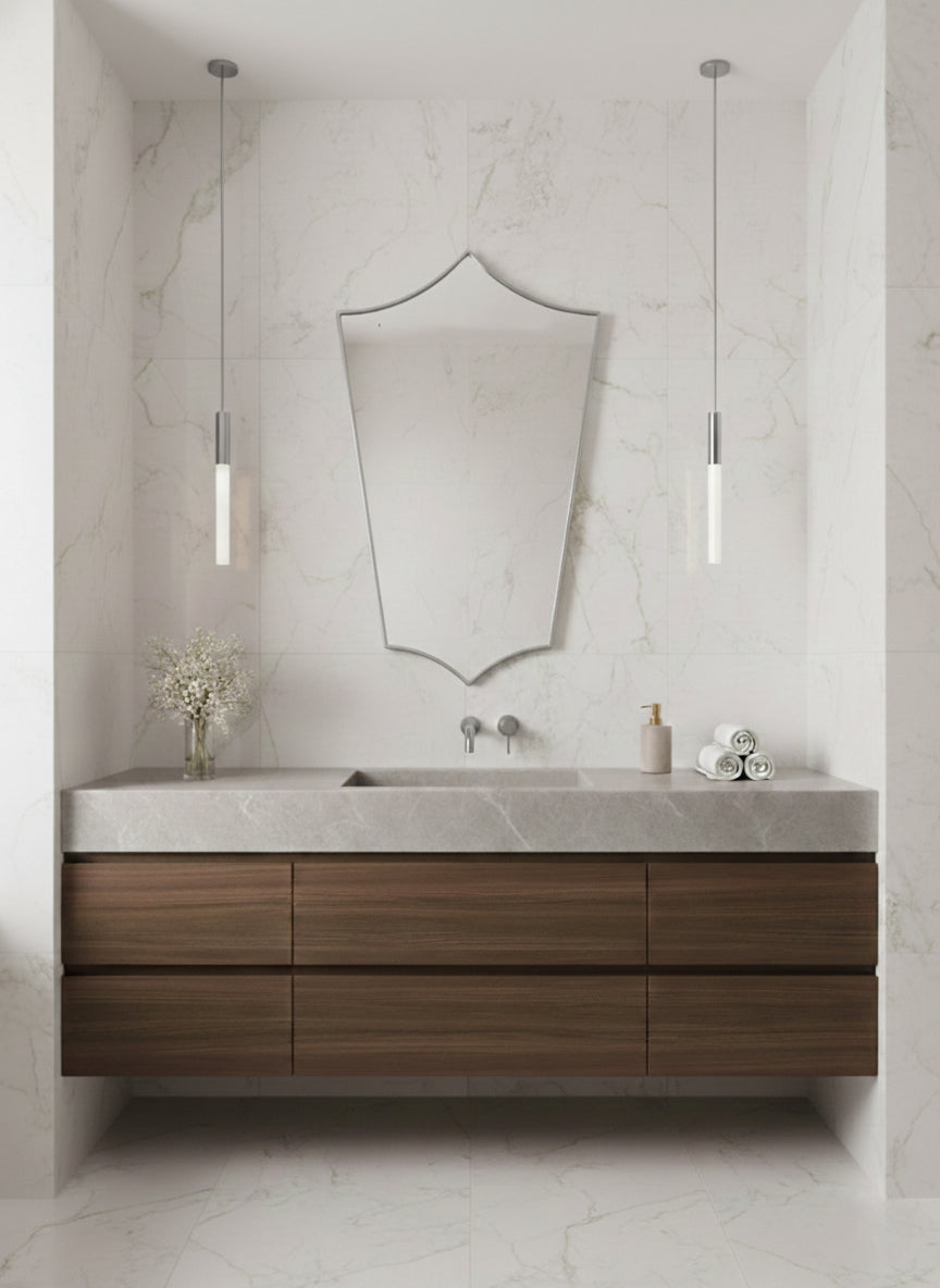 Silver brass shield mirror above wood floating vanity in marble bathroom.