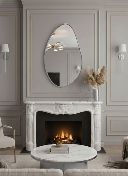 Silver asymmetrical brass mirror above fireplace.