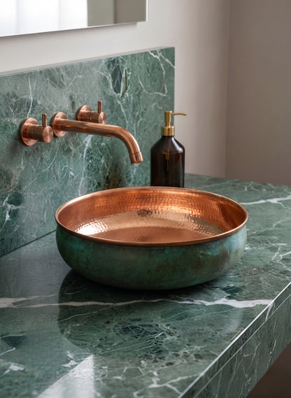 Copper vessel sink on green marble with wall-mounted faucet