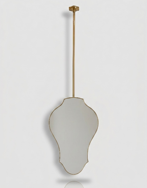 Decorative brass mirror with sculptural silhouette suspended from a ceiling-mounted brass rod.