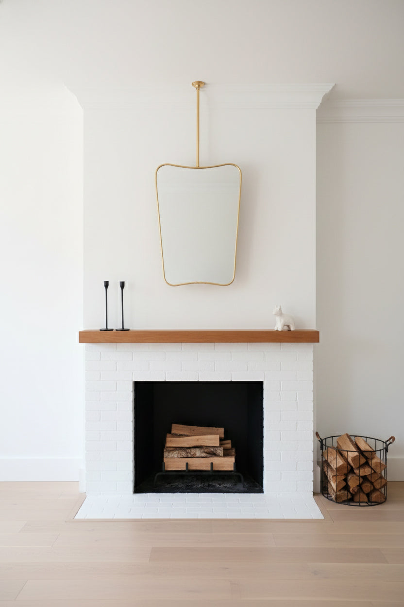 Suspended brass butterfly mirror above a white mantel fireplace