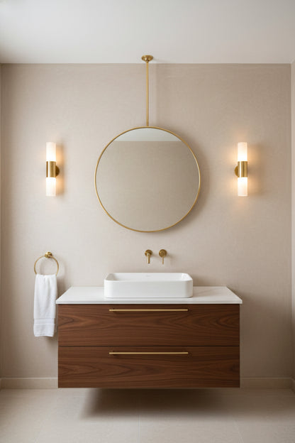 Suspended round brass mirror above a modern vanity with sconces