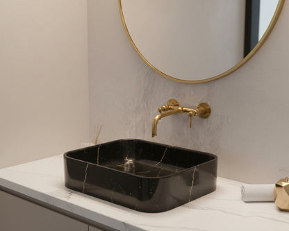 wall mounted faucet above a black marble sink 