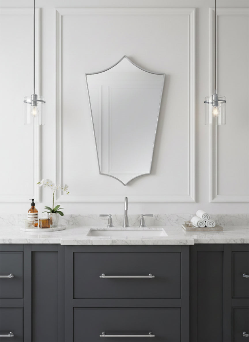 Elegant shield mirror over gray vanity in a classic white bathroom.