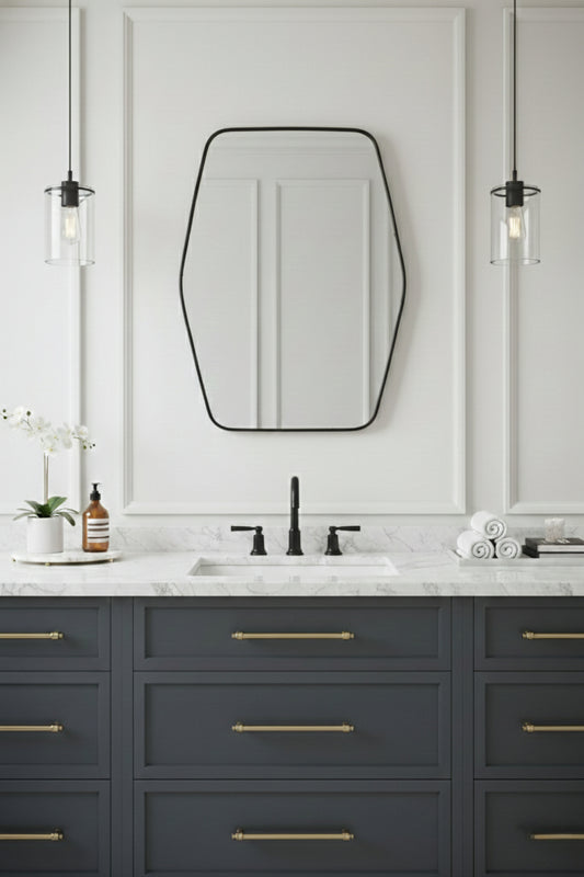 Modern hexagonal brass mirror over gray bathroom vanity with pendant lights.