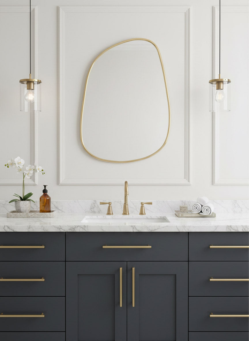 Organic brass mirror above navy double vanity with marble countertop and brass fixtures.