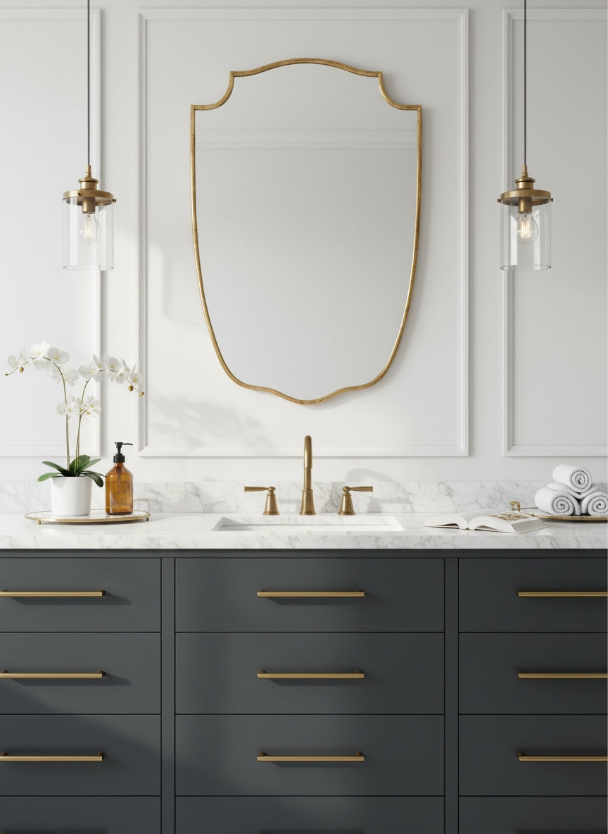 Brass shield mirror above dark blue bathroom vanity.