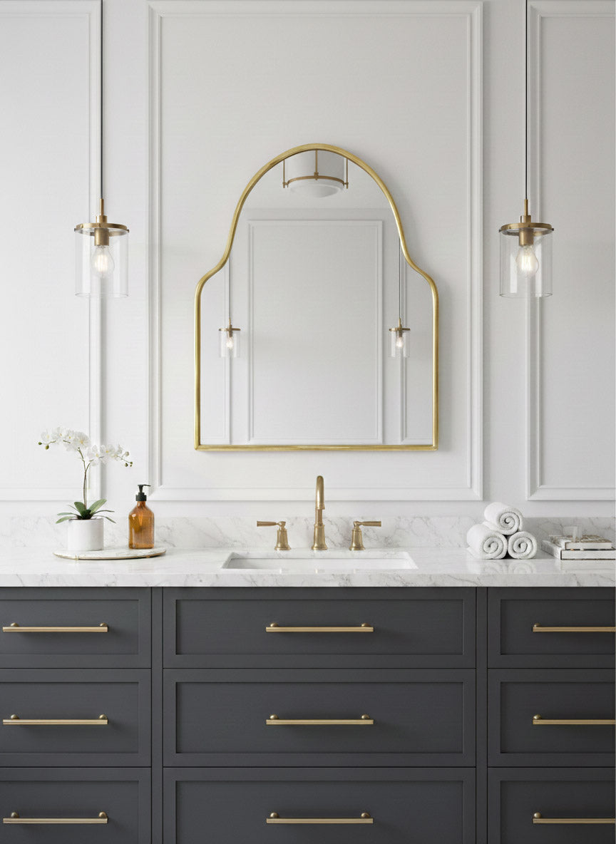 Brass mirror centered above navy vanity in modern classic bathroom