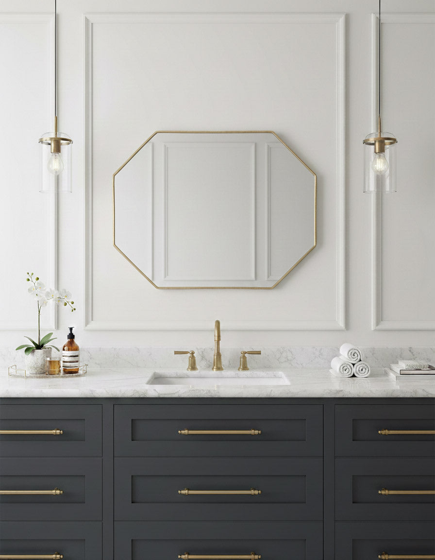 Octagon brass mirror above dark blue bathroom vanity.