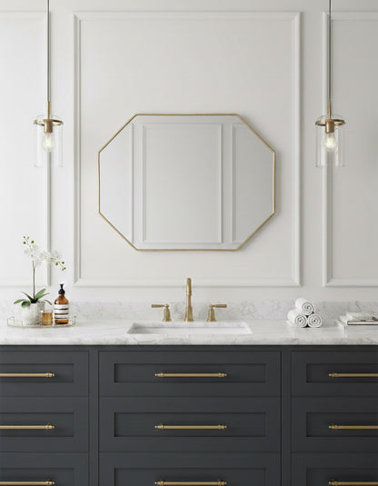 Octagon brass mirror above dark blue bathroom vanity.