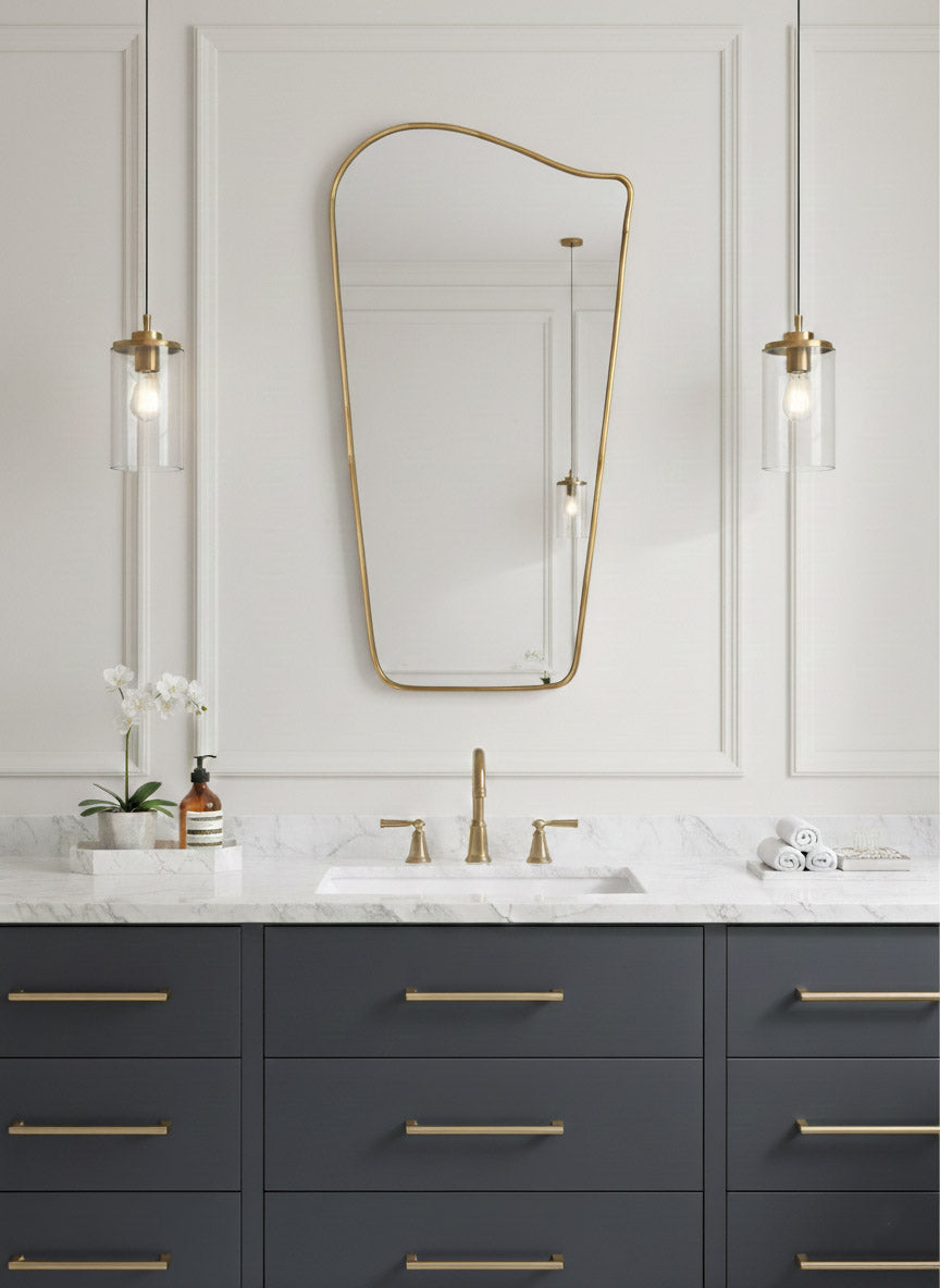 Wave brass mirror mounted over dark vanity in modern bathroom