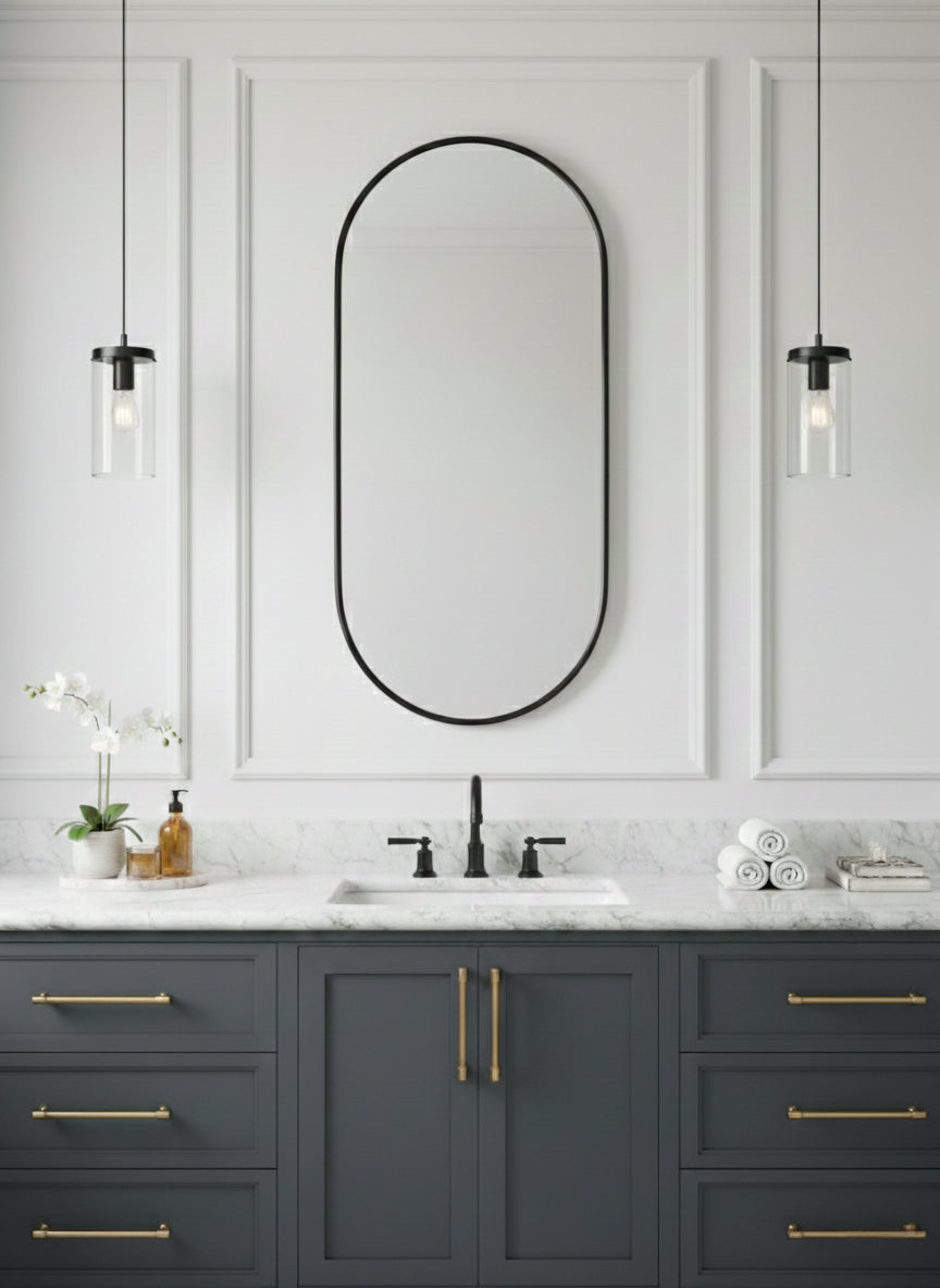 Black oval mirror above gray bathroom vanity.